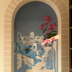 Adding the vibrant pink bougainvillea. This splash of color brings the scene to life, contrasting beautifully with the cool blues and whites of the Greek village.