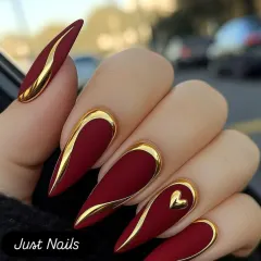This design is all about bold sophistication. A matte crimson base on sharp, stiletto nail extensions is accented with raised, metallic gold lines and a single gold heart. It's a powerful and luxurious look, perfect for a glamorous reception or cocktail event.