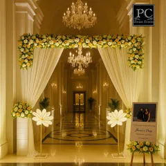 A grand and luxurious entrance for an engagement ceremony. A beautiful floral archway and elegant white drapes welcome guests into a stunningly lit corridor, setting a tone of opulence and celebration.