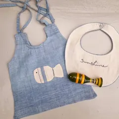 Another variation of our newborn gift set, this one features a fish applique on a blue hand-dyed Kora cotton dress, paired with a matching Channapatna fish rattle. It's a perfect example of creative collaboration.