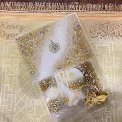 An elegant gift set in white and gold, perfect for Eid or any special occasion. This set includes a resin Quran box, a matching bookmark, and other accessories, all embellished with crystals and pearls for a luxurious finish.
