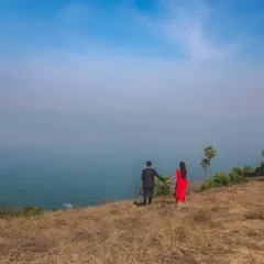 An epic wide shot of a couple holding hands on a cliff, overlooking the expansive sea. This image captures a feeling of adventure and the beginning of a shared journey.