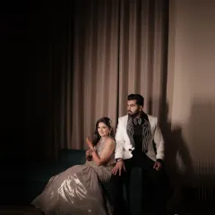 A high fashion, editorial style portrait of the couple. The dramatic lighting and their confident poses create a look of modern luxury for their cocktail party.