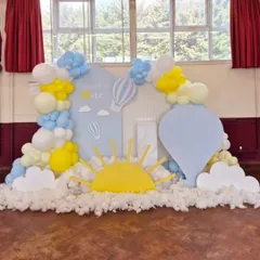 A dreamy "Up, Up and Away" theme for a first birthday, using soft blue and yellow balloons, cloud cutouts, and hot air balloon props to create a whimsical sky scene.