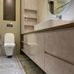 We used large, glossy marble-finish laminate for the vanity in this bathroom, paired with beautiful patterned floor tiles. The design includes a mix of open and closed storage for functionality.