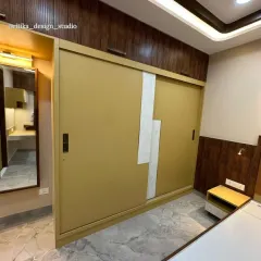 This image shows the custom sliding wardrobe, where the mustard yellow finish is paired with a textured white accent and a dark wood frame. The full-length mirror on the side is a practical addition that also helps to make the space feel larger.