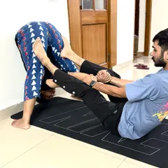 The journey into deep forward bends like Kurmasana, or Tortoise Pose, is a gradual process of release. In this photo, I am helping a client find length in their spine and open their hips using gentle, steady support. This partner-assisted stretching technique helps release tension in the lower back and hamstrings.