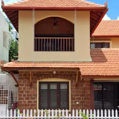 The exterior of the Basavanagudi house, featuring a combination of exposed laterite stone on the ground floor and smooth lime plaster on the first floor.