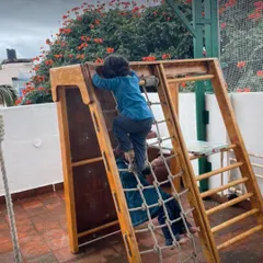 A child confidently navigates the climbing net on our wooden play structure. This kind of unstructured play is essential for building physical confidence and coordination.