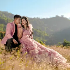 A romantic portrait of a couple on a sunlit hill, with the bride in a flowing pink gown. This highlights our work with destination shoots in beautiful natural landscapes.