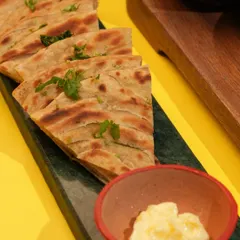The perfect companion to any curry, my Lachha Parathas are flaky, layered, and brushed with ghee. Here they are served with a side of white butter.