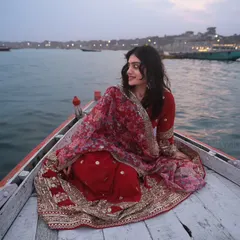 A candid moment on the Ganga. The model's glance over her shoulder and the flowing red fabric create a sense of effortless grace and movement.