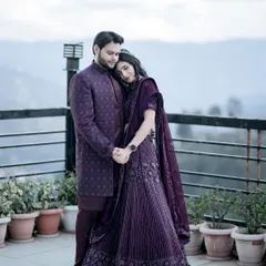 Here, the couple stands against a backdrop of misty mountains, their coordinated deep purple outfits adding a touch of royalty to the natural landscape. This full-length portrait captures a sense of quiet elegance and the grandeur of a destination shoot.