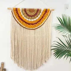 A full view of the half-moon wall hanging, showing how its long, flowing fringe adds a sense of calm and elegance. It hangs beautifully on a natural wood dowel and brings a touch of sunset warmth indoors.