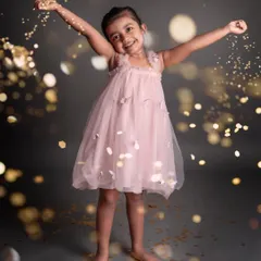 A moment of pure, carefree joy. This little girl's happiness is infectious as she plays with golden confetti in her beautiful pink dress.