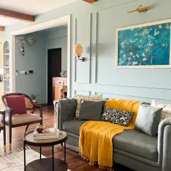We created a warm, farmhouse chic living room that feels like a weekend getaway. The design combines cozy textures, soft sage green walls for a calming effect, and a bright yellow throw for a pop of cheerful color. My goal is to design living spaces that feel like a warm hug, with beautiful and effective lighting.
