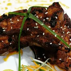 A close look at my smoked and glazed pork ribs. Each piece is cooked to be tender with a charred, flavorful exterior, then garnished with sesame.