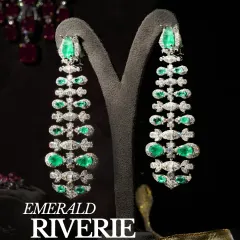 The Emerald Riverie earrings, a cascade of natural round and baguette diamonds with vibrant emeralds set in 18K gold. These long, articulated earrings move with you, creating a fluid and mesmerizing effect.