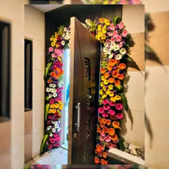 A bright and cheerful floral arch around a doorway, perfect for a home celebration. The mix of colorful gerbera daisies creates a lively and welcoming atmosphere right from the entrance.