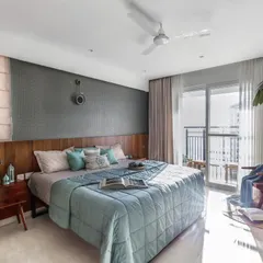 The full view of the master bedroom, which opens onto a balcony, allowing for ample natural light. The placement of a comfortable reading chair and plant by the window creates a perfect spot to relax.