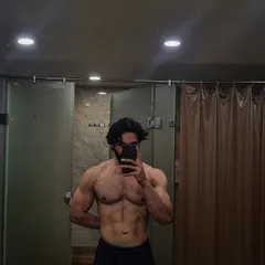 A member showing off his ripped physique in the changing room after a workout. Hard work truly pays off.