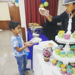 A young guest is delighted to receive a freshly made pizza slice, topped just the way he likes it, right next to our colorful cupcake display.