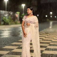 An ethereal shot of a woman in a delicate white saree, taken during a monsoon evening. The rain adds a touch of magic and romance to the scene.