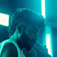 A close-up, atmospheric shot of me on the mic under cool blue lighting. The focus is on the connection between me, the music, and the crowd.