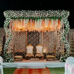 A surreal mandap design featuring a canopy of suspended florals and a geometric golden backdrop. The seating is regal, fit for a king and queen.