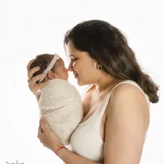 A mother's gentle gaze says it all. This simple, high-key portrait against a white background beautifully captures the intimate connection between a mother and her new baby.