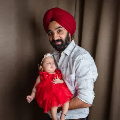 A proud father holds his sleeping daughter, his whole world in his arms. This simple, heartfelt portrait showcases the strength and tenderness of a dad's love.