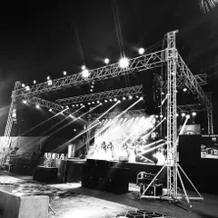A black and white shot of a stage truss and lighting rig, highlighting the structural engineering that goes into every concert setup. Safety and stability are our top priorities.
