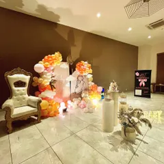 A wider view of the 'Baby in Bloom' baby shower, showing the full arrangement of the backdrop, throne chair for the mom-to-be, and the cake display plinths.