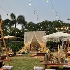 An enchanting bohemian sundowner setup, complete with low seating, macrame details, and pampas grass, all under a canopy of twinkling lights. This wide view captures the relaxed, yet utterly chic, vibe of the entire event.