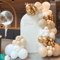 A classy and neutral-toned balloon decoration. The white arched backdrop is framed by a beautiful garland of white, cream, and chrome gold balloons, perfect for a baptism, naming ceremony, or elegant birthday.