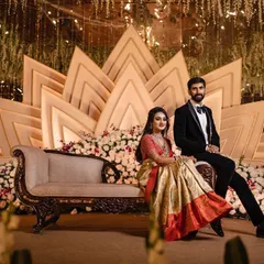 A wide shot of the couple seated on their reception stage, capturing the full splendor of the decor from a distance.