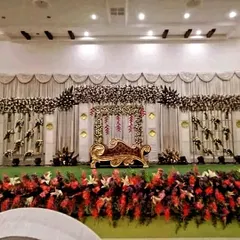 This is an example of our classic and opulent floral stage design. The combination of a grand floral canopy, intricate side arrangements, and a regal golden chaise lounge creates a focal point of pure elegance.