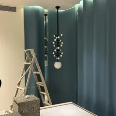 The same custom light fixture, seen from a different angle. The ladder and unfinished floor show the reality of a site in progress.