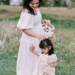 A mother and daughter moment during a maternity session. The little girl holds her teddy bear while her mom gently strokes her hair, a sweet interaction between them before the new baby arrives.