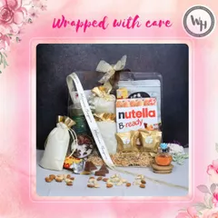 A hamper wrapped with care, ready to be gifted for any special occasion. This clear-lidded box is filled with Nutella B-ready, almonds, scented candles, and other treats, all nestled in shredded paper and tied with my signature ribbon.