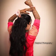 An artistic shot of the bride showing off her elaborate mehndi design, with her arms raised in a graceful pose.