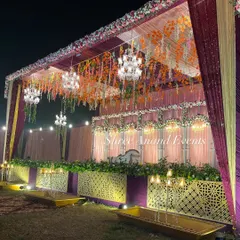 A closer view of a grand wedding stage, highlighting the lush greenery at the base and the cascading floral arrangements from the top.