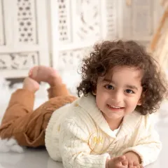 An adorable portrait of a toddler with beautiful curly hair. I use simple, clean backgrounds to let your child's personality shine through.