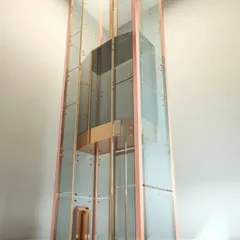 This rose gold capsule lift is an example of a bespoke design element that elevates an entire space. It acts as a functional sculpture, adding a touch of luxury and modern engineering to the interior.
