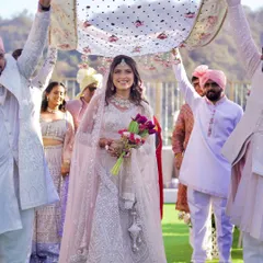 A bride making her way to the mandap under a delicate, modern 'phoolon ki chadar'. This image highlights the blend of tradition and contemporary style in today's weddings.