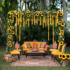 For a garden Haldi, I created this beautiful seating area using a wooden arch decorated with sunflowers and marigold strings. The vintage-style furniture and rustic rug complete the elegant and natural look.