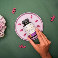 A top-down flat lay of Dr. Vedic Multivitamin for Women. The capsules are arranged like a clock around a pink plate, creating a playful and visually interesting composition.