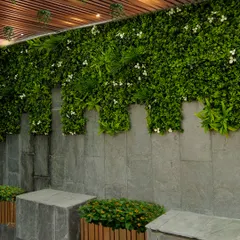 A vertical garden can completely change a space. Here, I used a combination of artificial greenery with small white flowers to cover a stone wall, creating a lush, maintenance-free feature that adds life and style under a slatted ceiling.