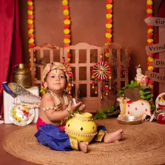 A sweet baby boy dressed as Kanha, sitting with his pot of butter in our traditional Janmashtami setup.
