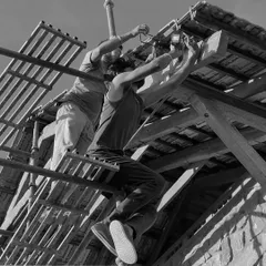 Perched on scaffolding, our team works on the details of a sloping roof against a stone wall. This is where design meets execution, rooted in nature and built by hand.